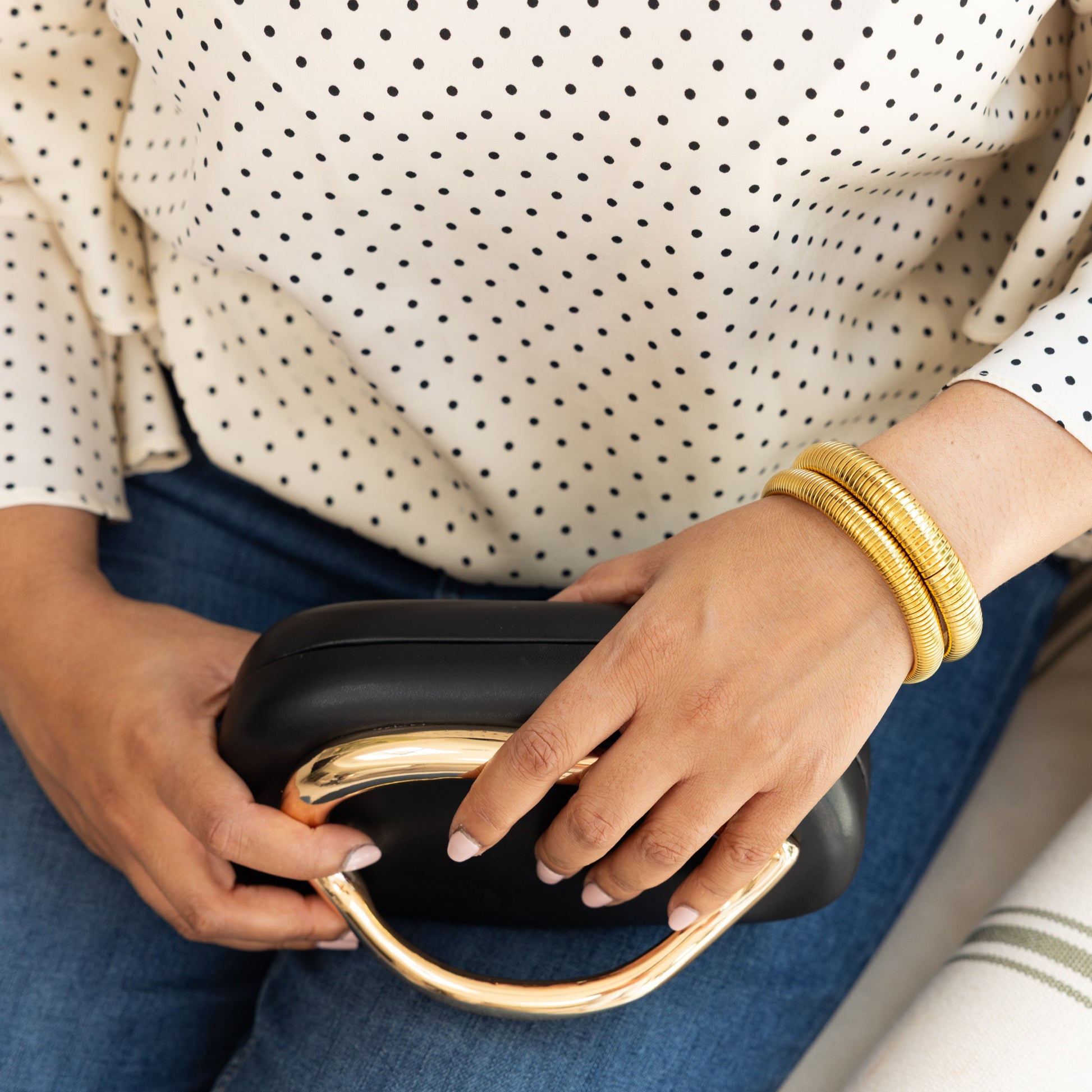 Person holding a black clutch with gold accents